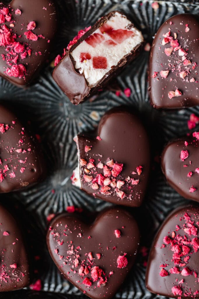 Heart-shaped chocolate truffles with pink sprinkles and creamy filling.