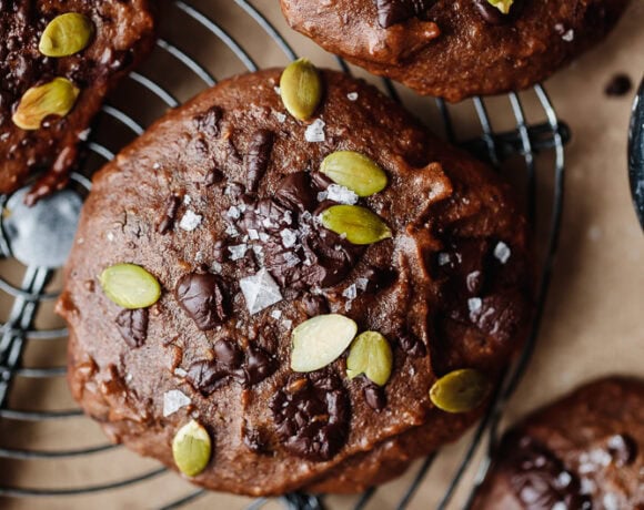 Chocolate muffins topped with pumpkin seeds and sea salt on a cooling rack.