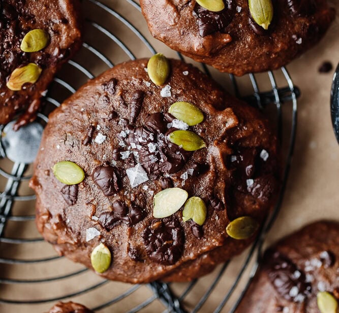 Chocolate muffins topped with pumpkin seeds and sea salt on a cooling rack.