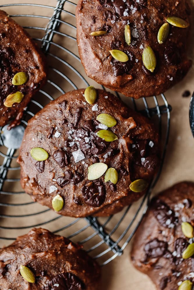 Chocolate muffins topped with pumpkin seeds and sea salt on a cooling rack.