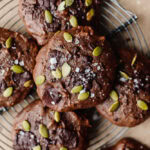 Delight Fuel chocolate cookies topped with pumpkin seeds and sea salt on a wire rack.