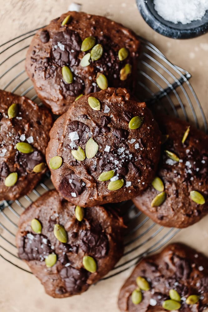 Delight Fuel chocolate cookies topped with pumpkin seeds and sea salt on a wire rack.
