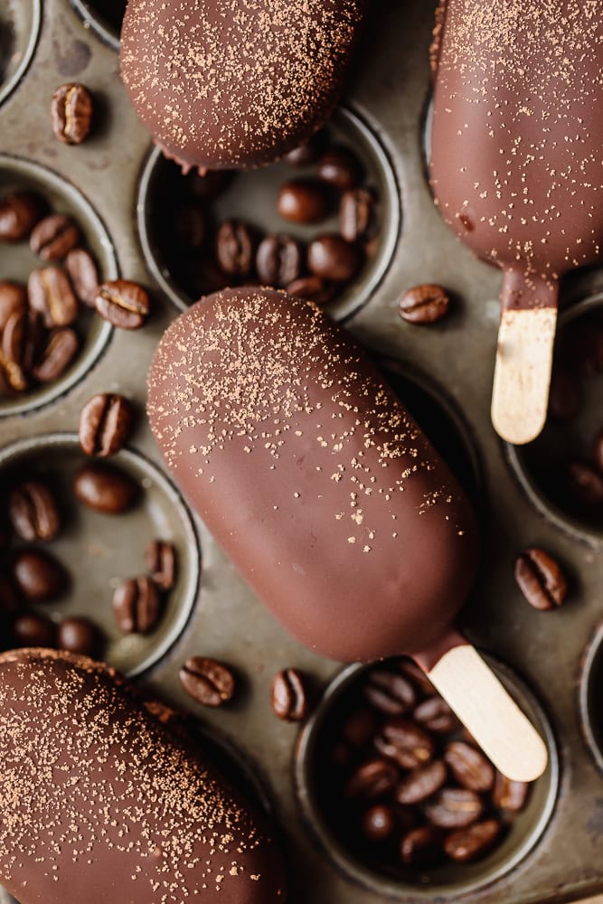 Chocolate coffee popsicles with coffee beans and gold dust on a tray.