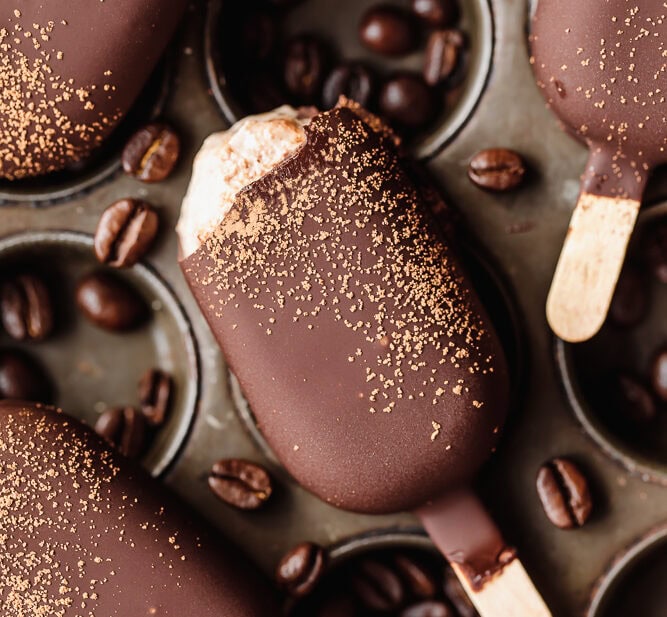 Chocolate popsicles with coffee beans and gold dust, close-up.