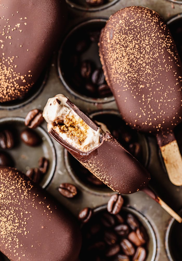 Chocolate-covered ice cream bars with coffee beans on a tray.