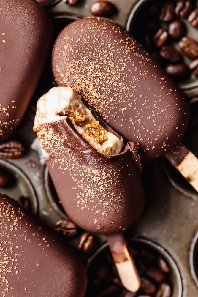 Chocolate-covered ice cream bars with coffee beans and cocoa powder.