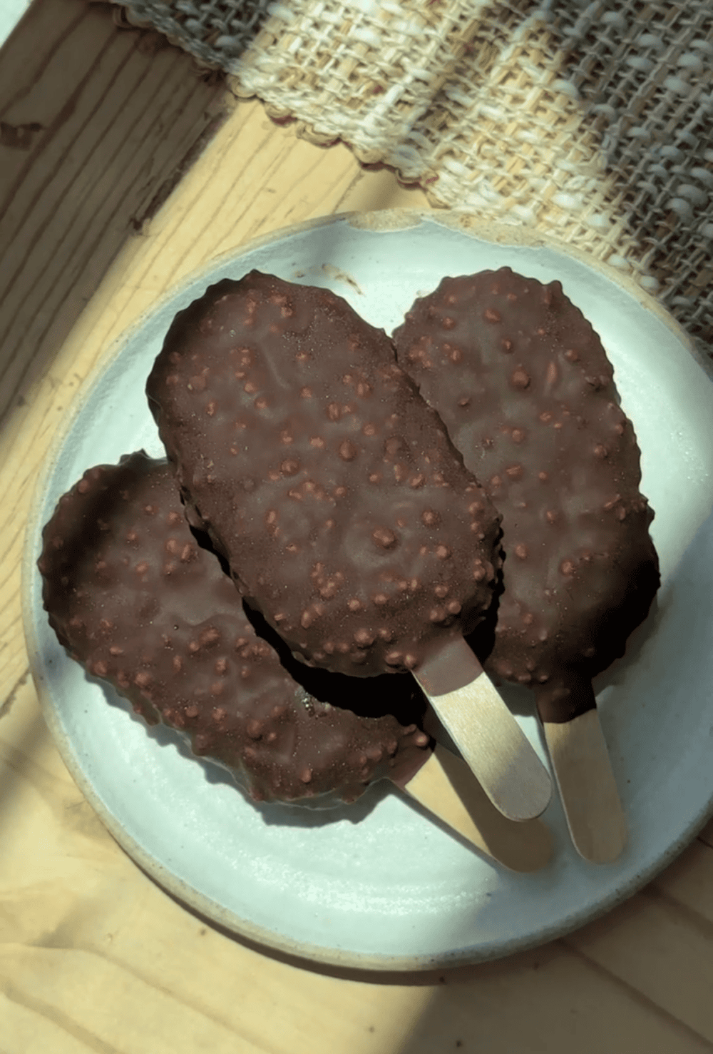 Chocolate ice cream bars with crunchy coating on a white plate.