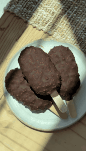 Chocolate ice cream bars with crunchy coating on a white plate.