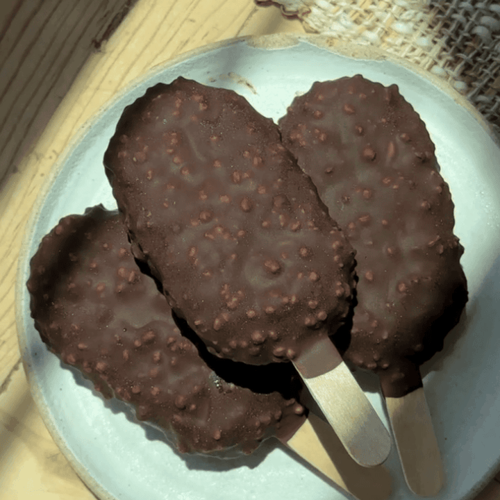 Chocolate ice cream bars with crunchy coating on a white plate.