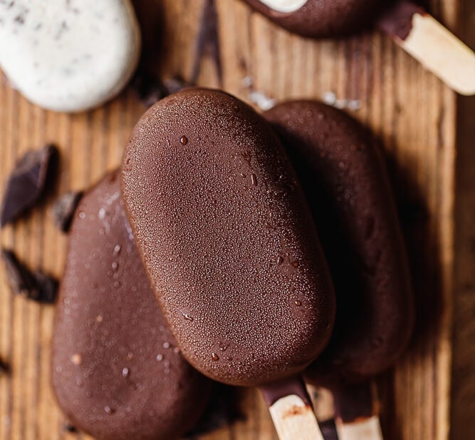 Chocolate and vanilla ice cream bars on wooden surface.