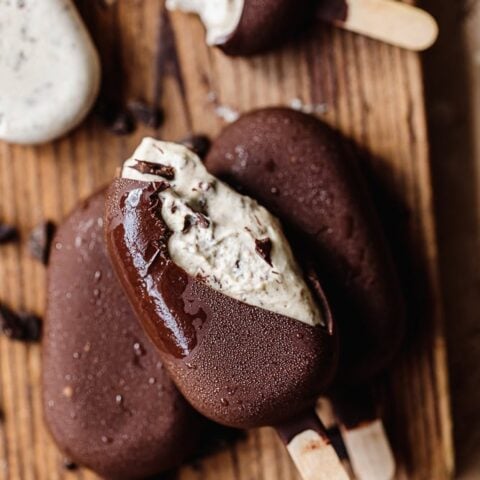 Chocolate ice cream bars with creamy filling on wooden surface.