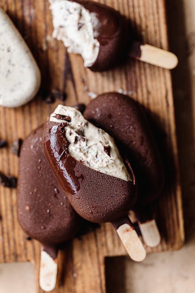 Chocolate ice cream bars with creamy filling on wooden surface.