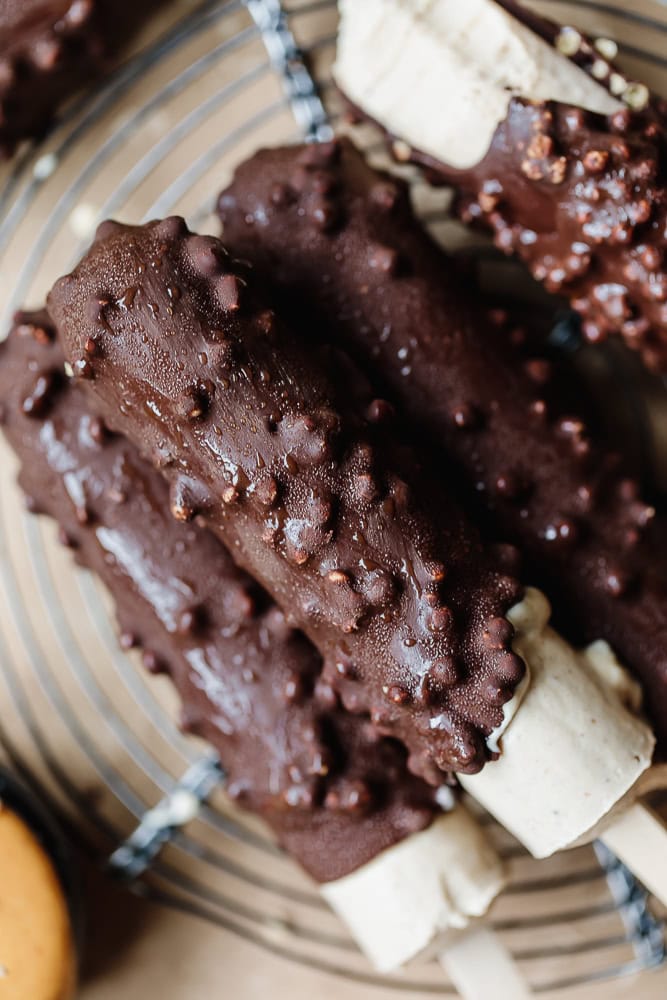 Chocolate protein bars with crunchy toppings on a wire rack.