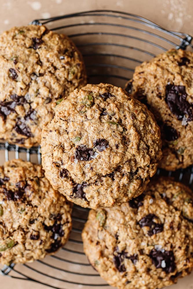 Freshly baked oatmeal cookies with chocolate chips on a cooling rack.