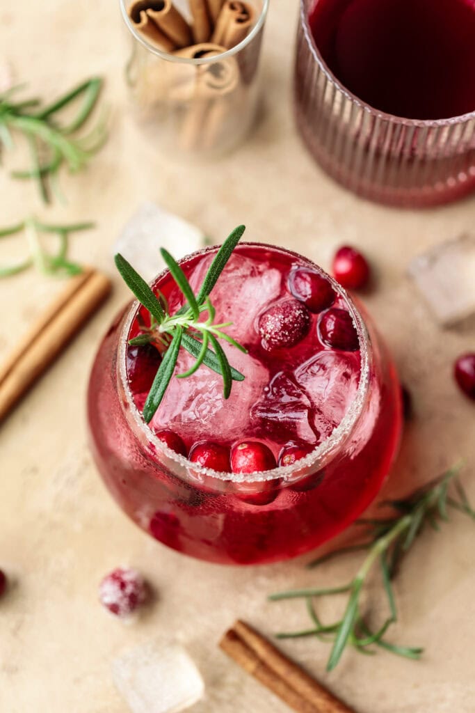 Refreshing cranberry cocktail with ice and rosemary garnish.